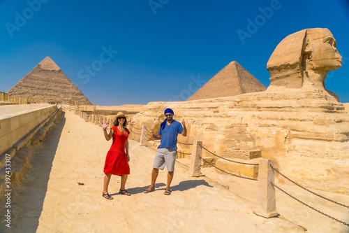 A tourist couple at The Great Sphinx of Giza and in the background the Pyramids of Giza, the oldest Funerary monument in the world. In the city of Cairo, Egypt