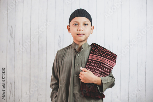 Portrait asian Muslim Boy wearing traditional costume called gamis  looking at camera get ready to pray photo
