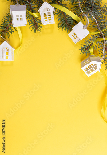 Christmas, New Year festive background with green fir branches, Xmas lights white lodges on yellow. Top view. Christmas holiday decorations. Copy space for text. Vertical orientation.