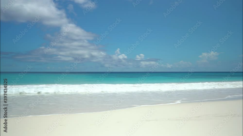 Exotic beach by the ocean with rolling waves on the sandy shore and blue sky Exotic beach by the ocean with rolling waves on the sandy shore and blue sky