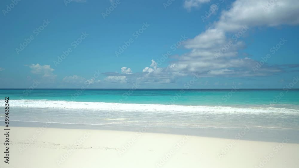 Exotic beach by the ocean with rolling waves on the sandy shore and blue sky Exotic beach by the ocean with rolling waves on the sandy shore and blue sky