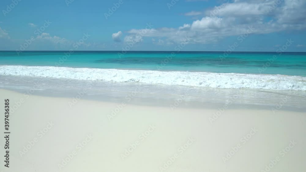 Exotic beach by the ocean with rolling waves on the sandy shore and blue sky Exotic beach by the ocean with rolling waves on the sandy shore and blue sky