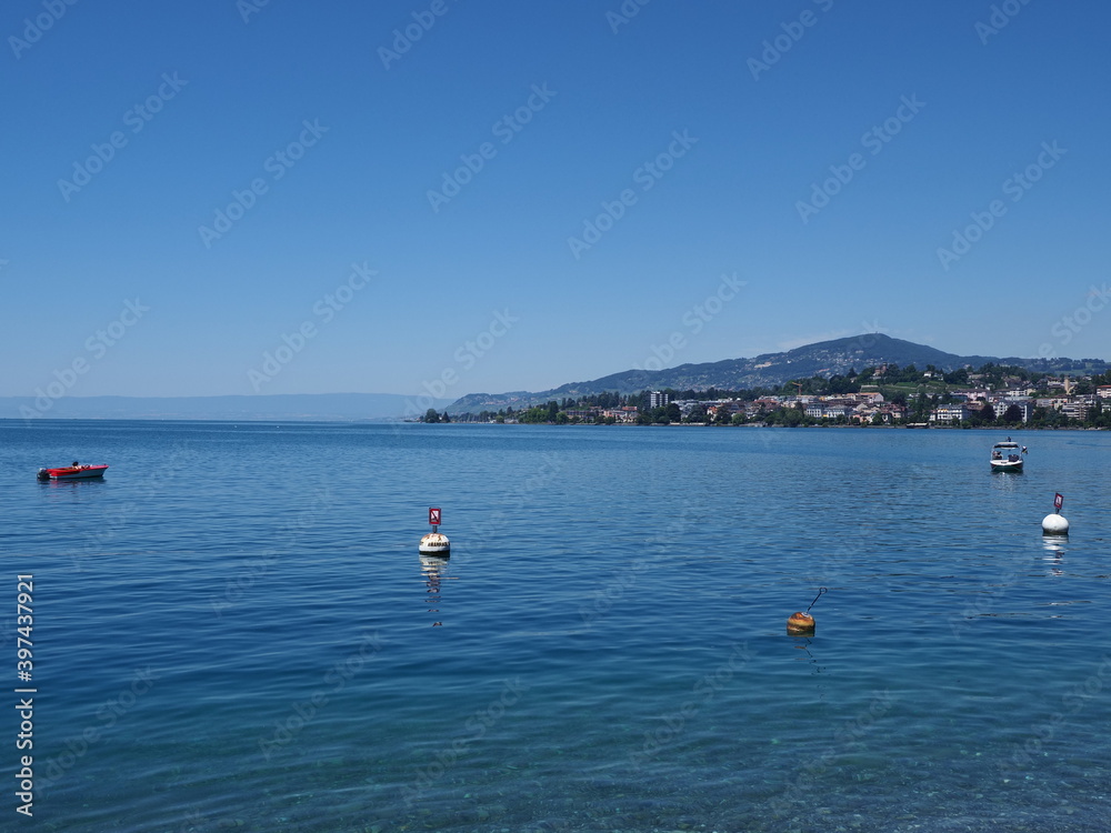 Boats on Lake Geneva and european Montreux city in canton Vaud in Switzerland, clear blue sky in 2017 warm sunny summer day on July.