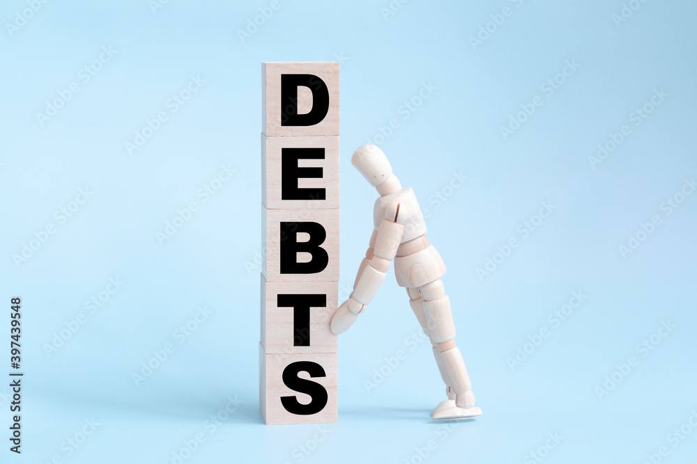 Cube block wood word debt and wooden man on blue background. Financial debt decrease concept. Cube block wood word debt and wooden man on blue background. Financial debt decrease concept.