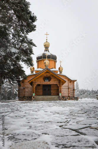 Fototapeta Naklejka Na Ścianę i Meble -  A wooden church stands in a pine forest. Snowy nature.