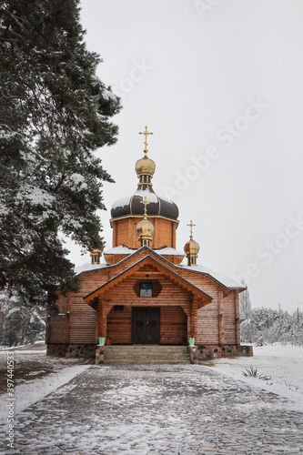Fototapeta Naklejka Na Ścianę i Meble -  Large wooden church. Golden domes. Around winter and pine forest.