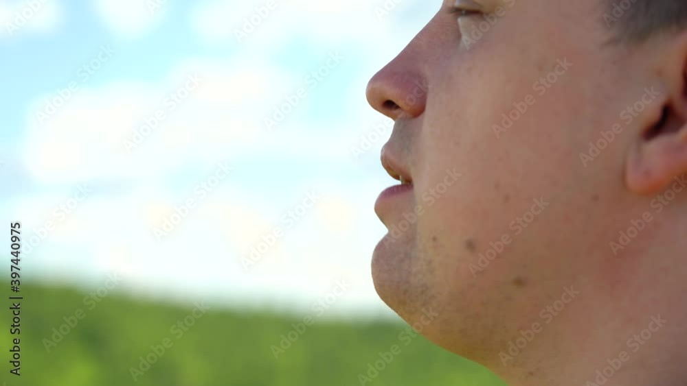 A fat young man of Caucasian appearance drinks water from a transparent plastic bottle against a blue sky with white clouds. Thirst quenching. Drink clean water from a bottle. Close-up. A fat young man of Caucasian appearance drinks water from a transparent plastic bottle against a blue sky with white clouds. Thirst quenching. Drink clean water from a bottle. Close-up.