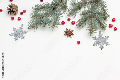 Christmas white background with fir branches, snowflakes, star anise and red cranberries