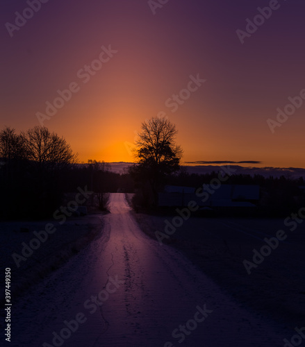 A beautiful winter morning landscape with a gravel road. Bright  extra colorful scenery of Northern Europe. Snow covered road in the rural scene.