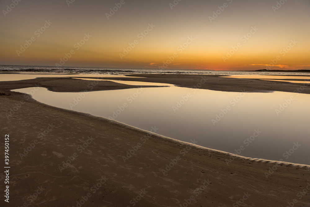Water ponds at a lonely beach during a golden sunset in the Uruguayan cost. 