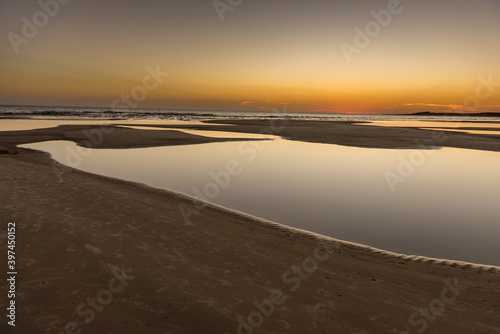 Water ponds at a lonely beach during a golden sunset in the Uruguayan cost. © Marquicio
