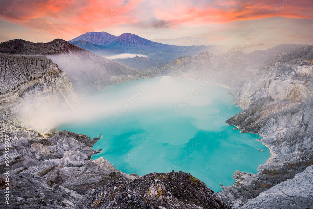 View from above, stunning aerial view of the Kawah Ijen volcano complex at sunset with the blue acid lake and some clouds of toxic gases raising from a sulfur deposit. East Java, Indonesia. View from above, stunning aerial view of the Kawah Ijen volcano complex at sunset with the blue acid lake and some clouds of toxic gases raising from a sulfur deposit. East Java, Indonesia.