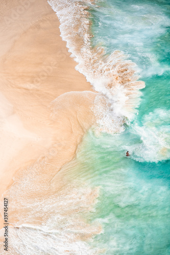 View from above, stunning aerial view of an unidentified person walking on a beautiful beach bathed by a turquoise sea. Kelingking beach, Nusa Penida, Indonesia.