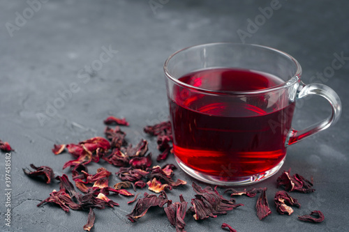 Hibiscus tea glass cup and dried flowers frame on gray concrete background. Vitamin, recipe, beverage concept. Close-up, copy space