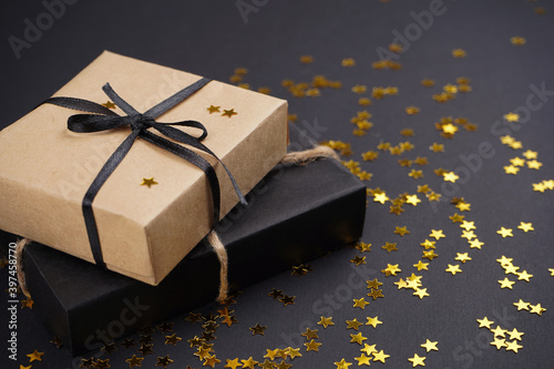 Craft gifts frame, golden star shape confetti on black background. Merry Christmas, New Year, magic concept. Close-up, copy space.