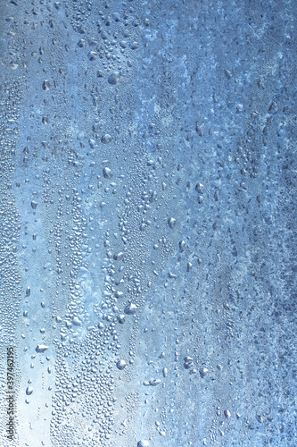Natural frozen drops of condensation on transparent glass. Beautiful background from a frozen window in winter. Drops texture on the glass