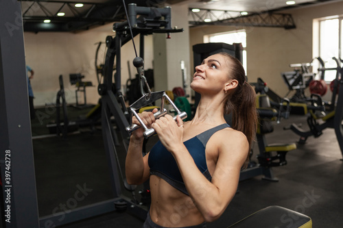 Foto Athletic muscular woman exercising her back in lat exercise machine with narrow