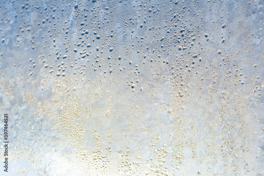 Natural frozen drops of condensation on transparent glass. Beautiful background from a frozen window in winter. Drops texture on the glass Natural frozen drops of condensation on transparent glass. Beautiful background from a frozen window in winter. Drops texture on the glass