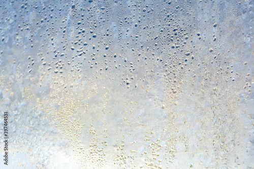 Natural frozen drops of condensation on transparent glass. Beautiful background from a frozen window in winter. Drops texture on the glass