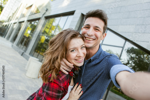 Selfie portrait of a cheerful funny couple in love. A couple is fooling around outdoors. Love concept