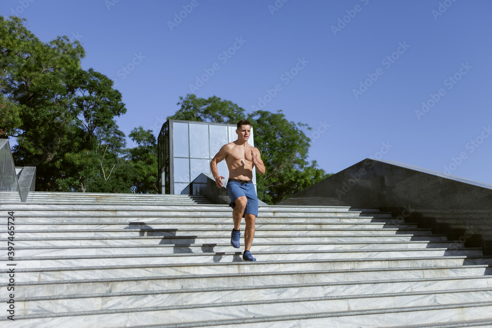 Young fit male runner jogging stairs outdoors. Cardio workout. Healthy lifestyle