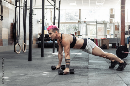 Young cross fit woman exercising with dumbbells. Push-ups. Functional training