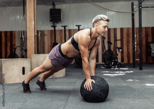 Fototapeta Naklejka Na Ścianę i Meble -  Muscular athletic woman push ups with medicine balls in a modern gym. Cross fit, functional training