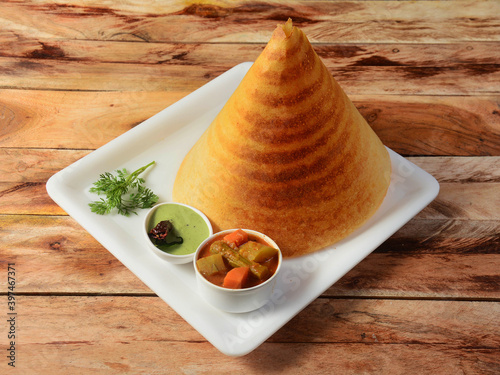 Plain Dosa, a south Indian traditional and popular Breakfast served with chutney and sambar over a rustic wooden background, selective focus