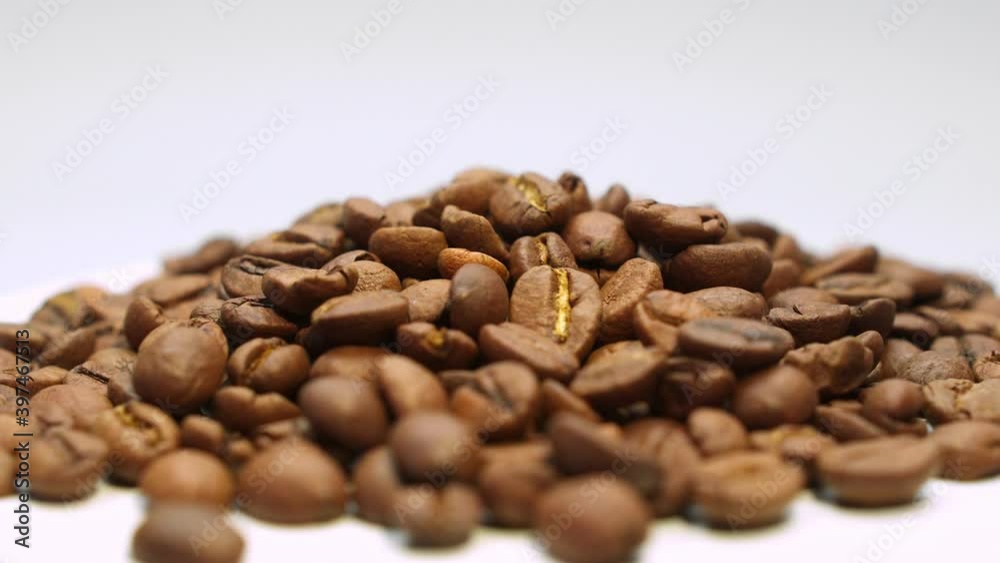 Close-up of pile of roasted coffee beans rotating on a white background. Ingredient for coffee. Close-up of pile of roasted coffee beans rotating on a white background. Ingredient for coffee.