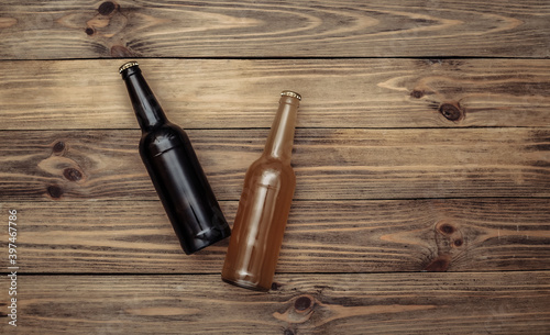 Two bottles of dark and light beer on wooden background. Top view.