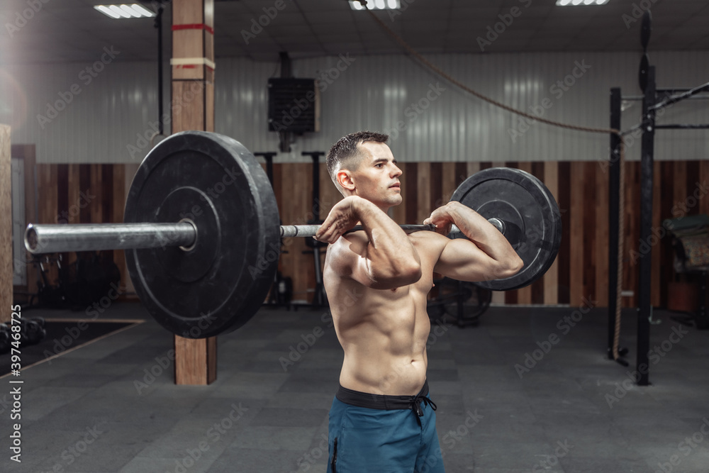 Athletic muscular man exercising with a heavy barbell in a modern health club. Bodybuilding and Fitness
