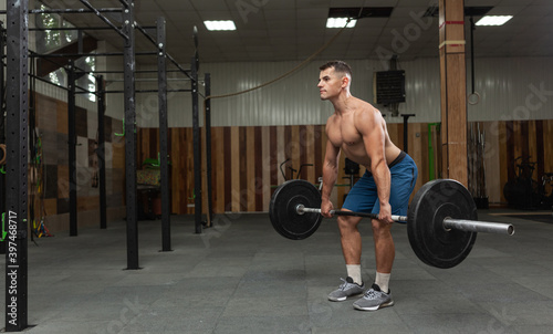 Muscular bodybuilding man doing deadlift exercise with a heavy barbell in a modern health club. Bodybuilding and Fitness