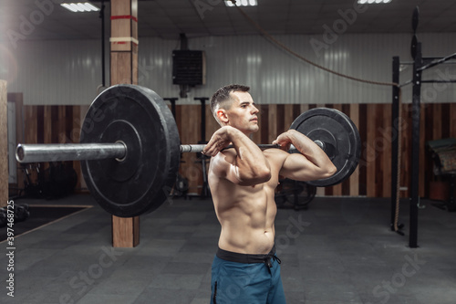 Athletic muscular man exercising with a heavy barbell in a modern health club. Bodybuilding and Fitness photo