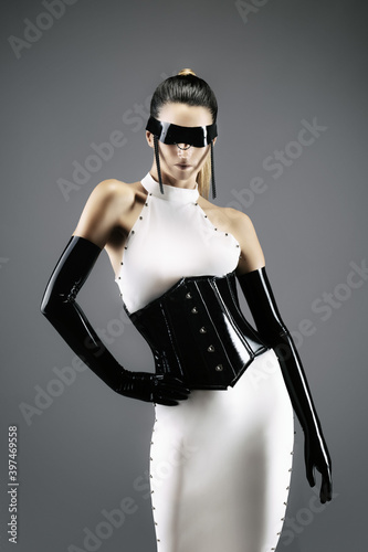 Futuristic portrait of a pretty young woman in a white dress, wearing a waist cincher, gloves and a black latex headband