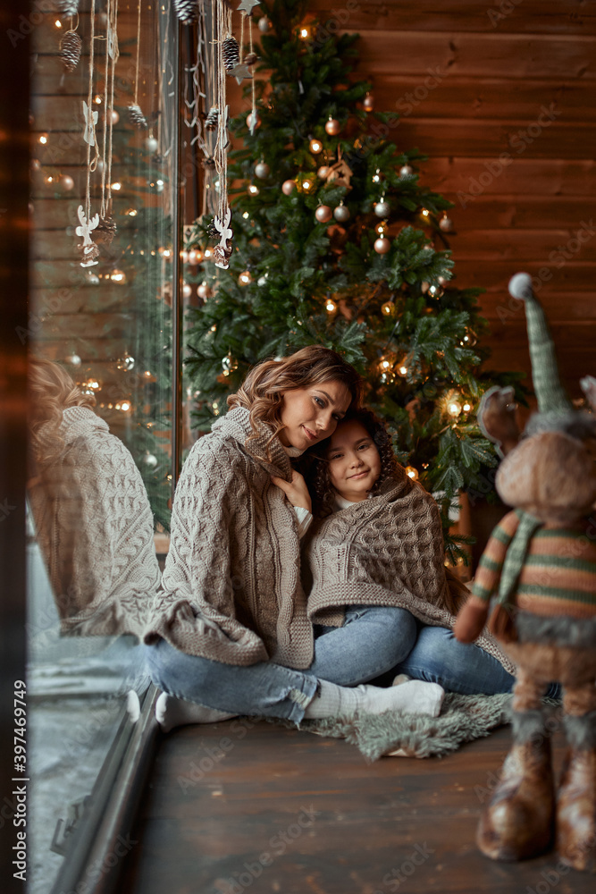 The pretty girl with mum are decorating a Christmas tree in the house. Happy family. The pretty girl with mum are decorating a Christmas tree in the house. Happy family.