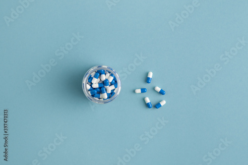 Flat layout of blue-and-white medical capsules with the same pills in small jar