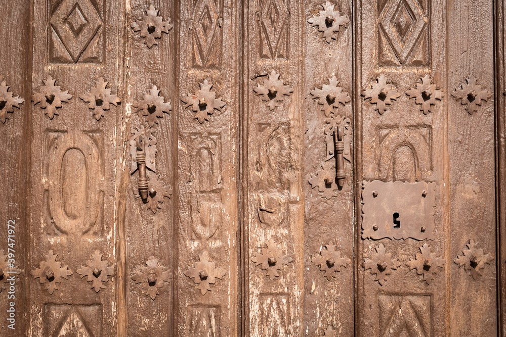 old brown wooden door with metallic ornaments	