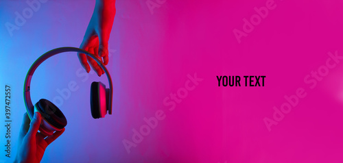 Photos Hands holding wireless stereo headphones with neon blue-pink gradient light