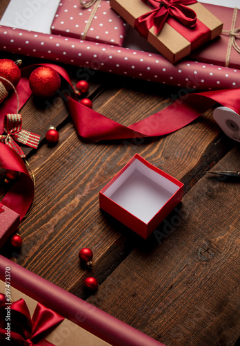 Gifts and red paper in wrapping time on wooden table