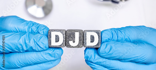 DJD Degenerative joint disease - word from stone blocks with letters holding by a doctor's hands in medical protective gloves