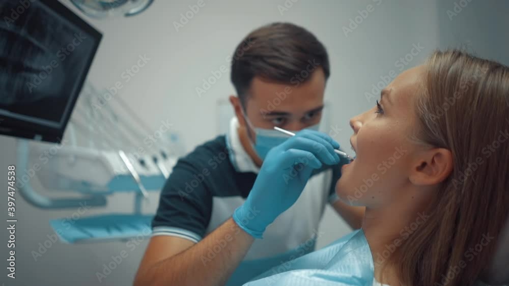 A male dentist in a protective medical mask using tools examines the patient's oral cavity. Dental treatment and care. Oral hygiene. Health care and medicine concept. A male dentist in a protective medical mask using tools examines the patient's oral cavity. Dental treatment and care. Oral hygiene. Health care and medicine concept.