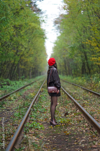 girl in red hat on railway in forest.