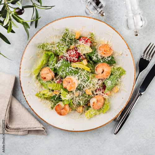 Fresh summer salad with shrimp, tomato and tomato lettuce ion a platel on light table. Concept of healthy eating. photo