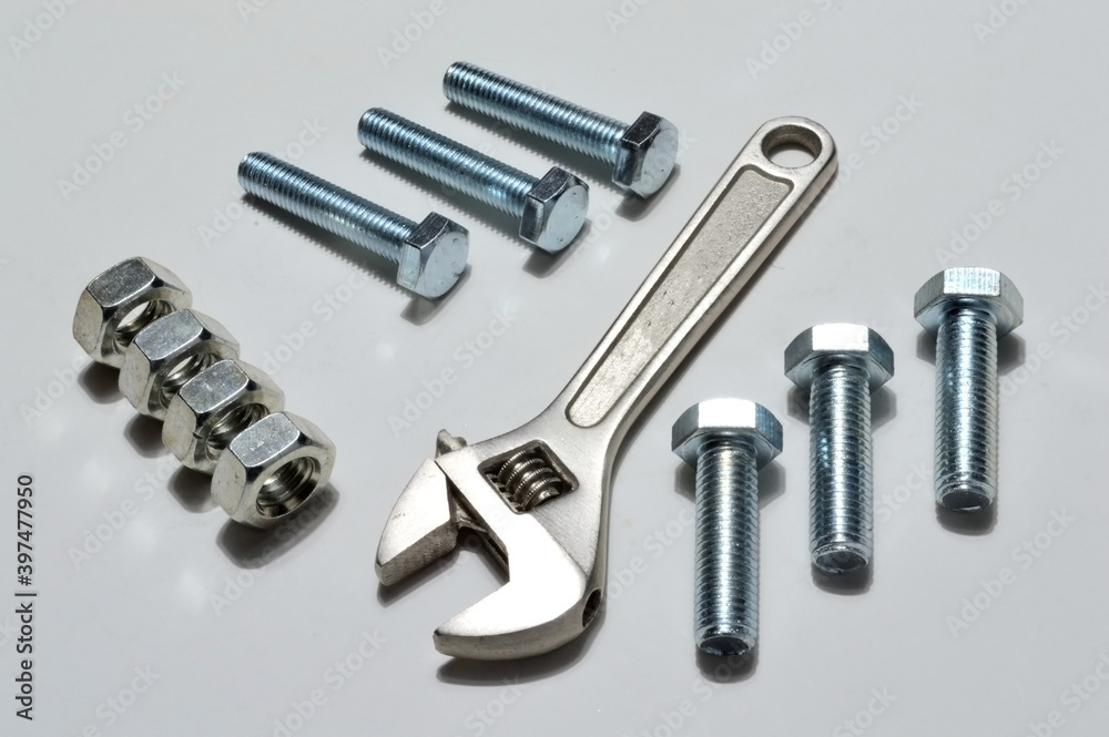 screw-nut of different sizes, bolts and adjustable spanner. White background. screw-nut of different sizes, bolts and adjustable spanner. White background.