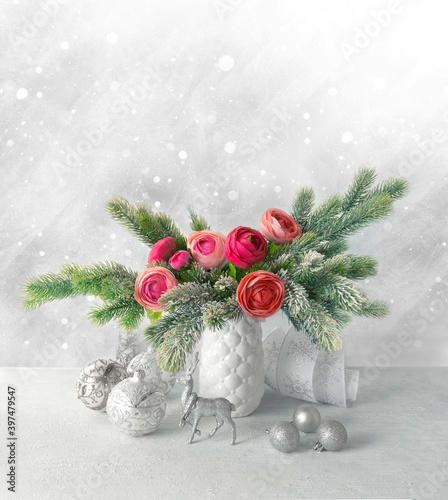 Festive winter flower arrangement with peonies and snow-covered fir branches in a vase on the table decorated for the holiday. Christmas or New Year concept