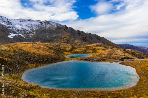 View of blue, alpine lake from April Bowl trail at Hatcher's Pass, Talkeetna Mountains, Alaska. The high altitude mountain lake is above treeline, and is surrounded by tundra.