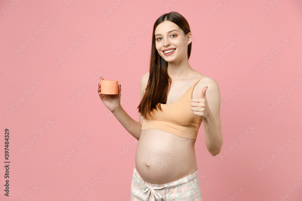 Pregnant woman future mom in top with belly stomach tummy with baby hold applying cream for stretch marks striae isolated on pink background studio Maternity family pregnancy expectation concept Pregnant woman future mom in top with belly stomach tummy with baby hold applying cream for stretch marks striae isolated on pink background studio Maternity family pregnancy expectation concept