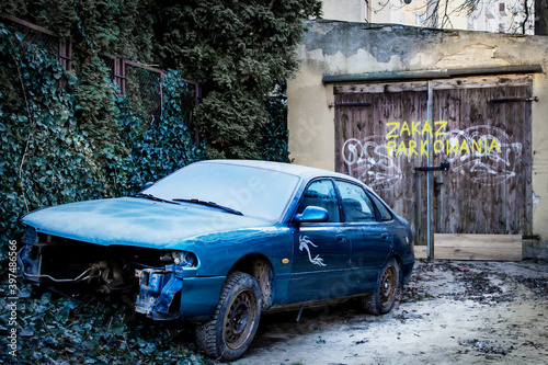 Zakaz parkowania, stare auto zaparkowane na zaniedbanym podwórku przy bramie garażowej