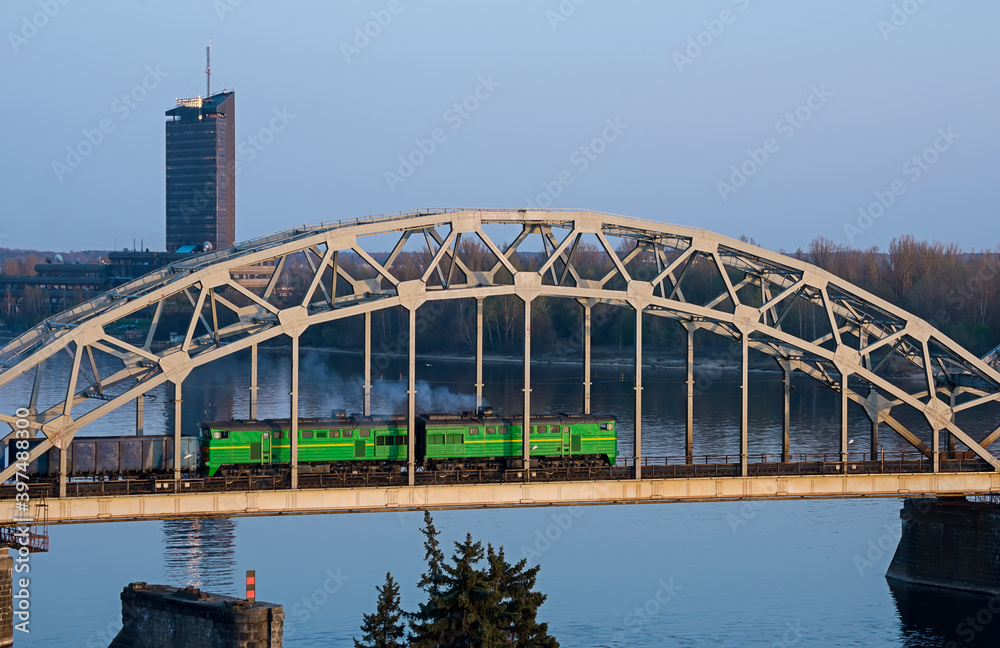 Fototapeta premium Electric train passing the bridge over Daugava in Riga