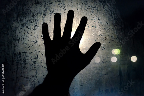 Help me please. A hand calling for help on the foggy night glass. Symbol of helplessness
